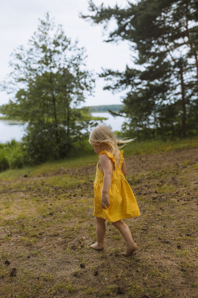 Girl in Yellow Dress Standing on Green Grass Field